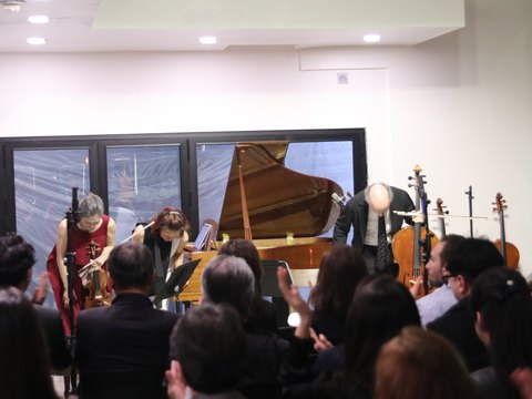 Three musicians bowing at the end of a concert while the audience applauds